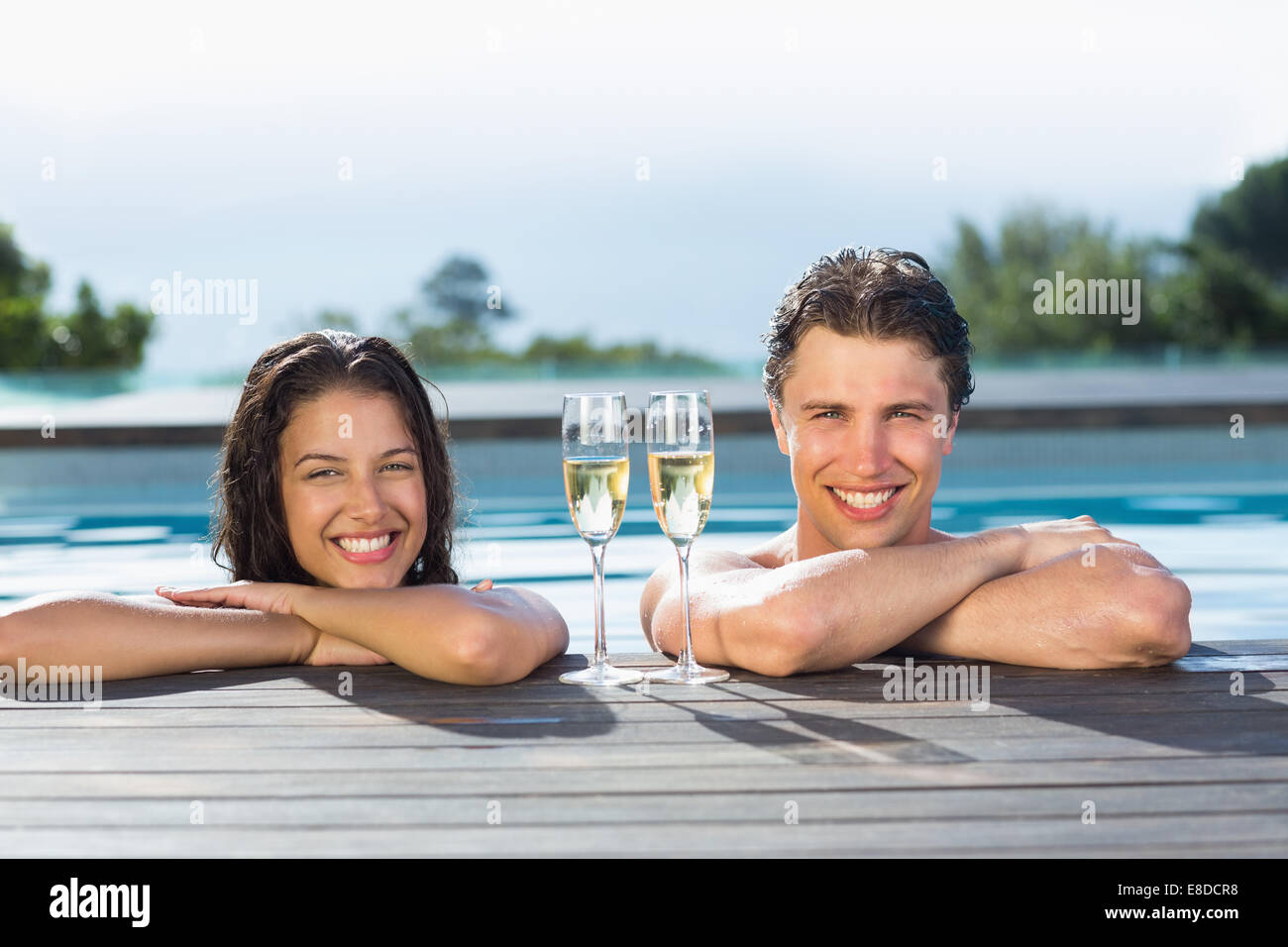 Couple with champagne flutes in swimming pool Stock Photo