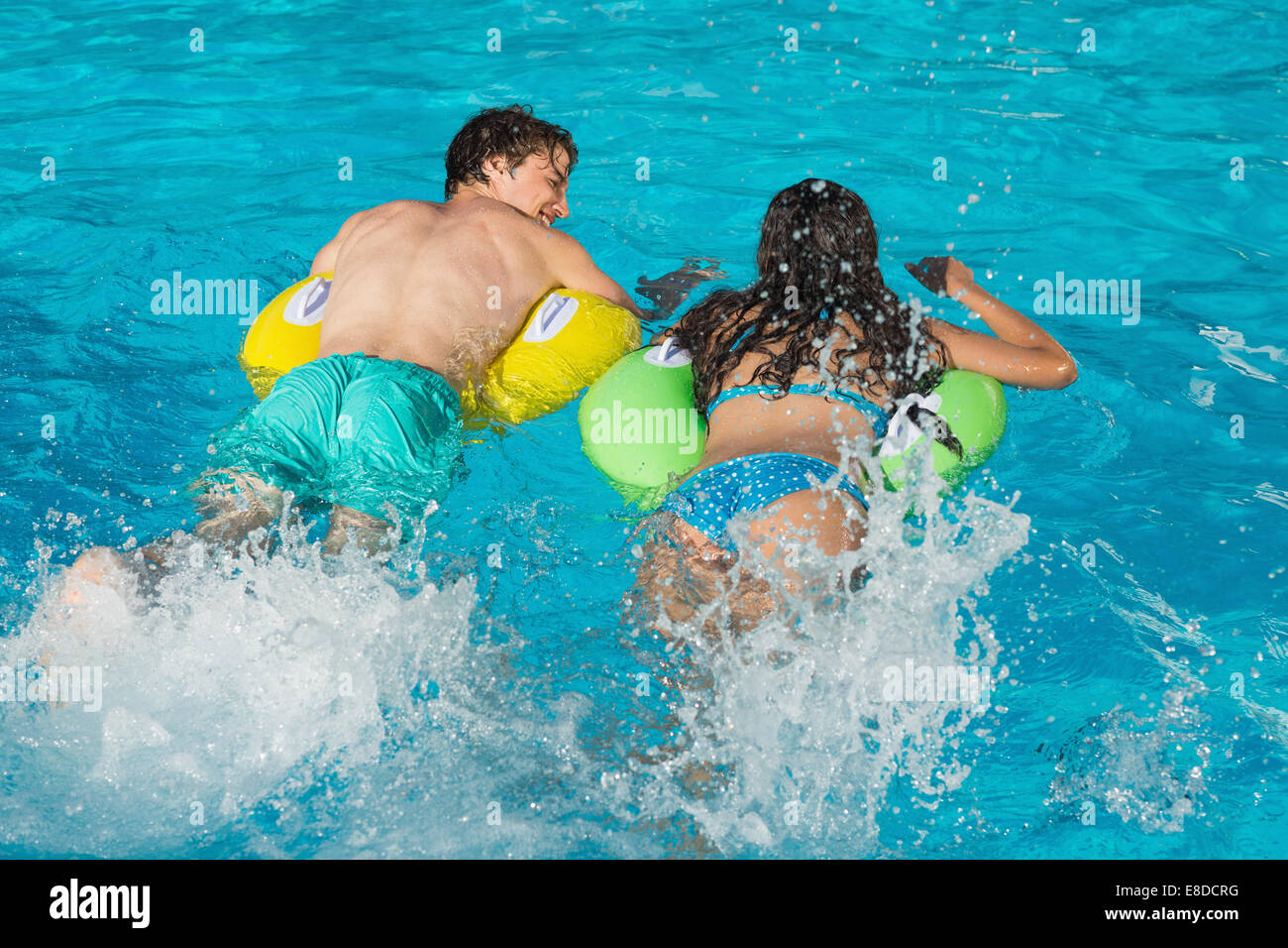 Couple in inflatable rings at swimming pool Stock Photo