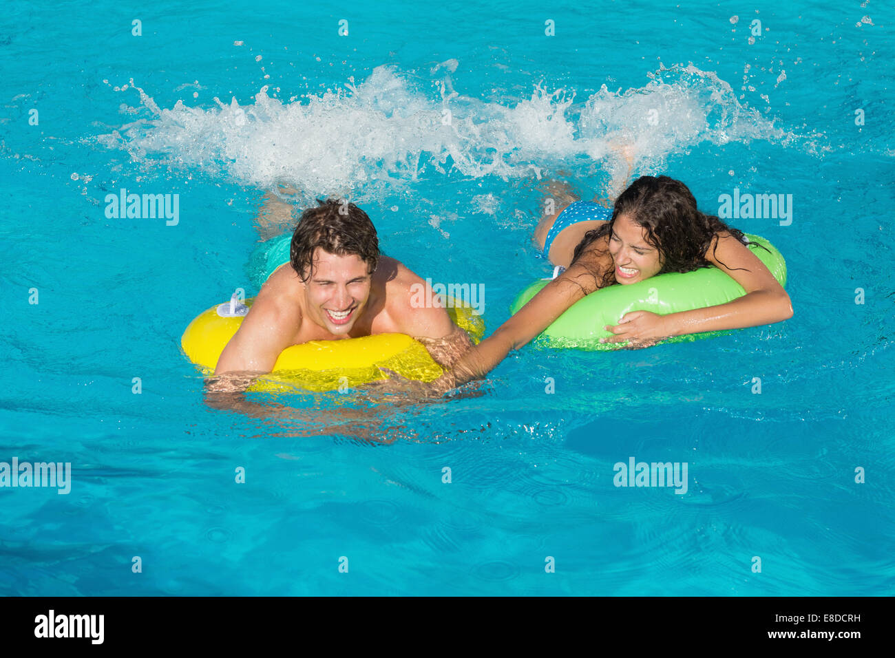 Couple in inflatable rings at swimming pool Stock Photo