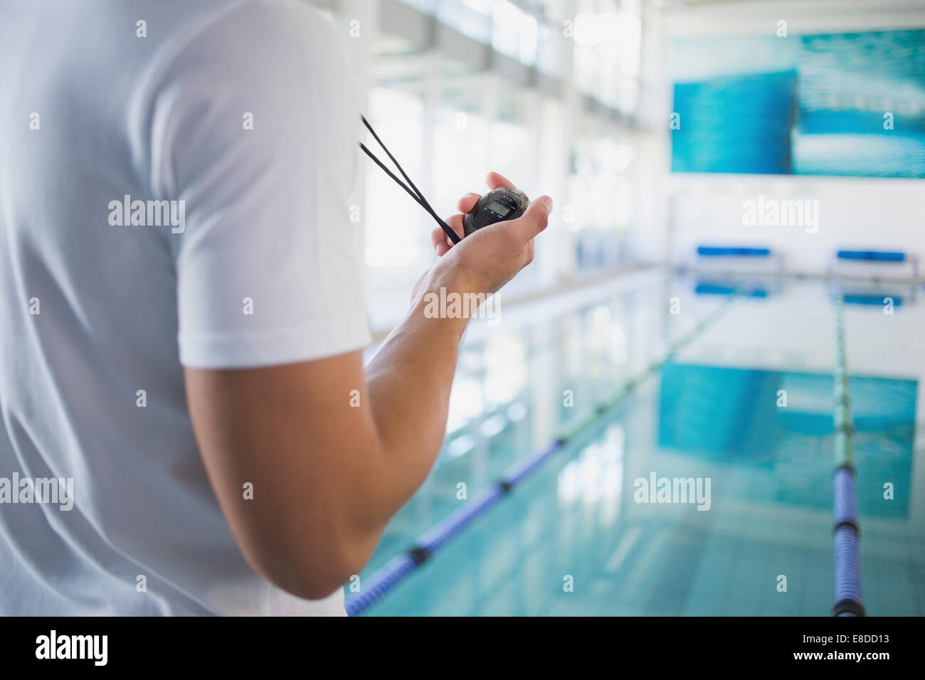 Swimming instructor holding stopwatch by the pool Stock Photo