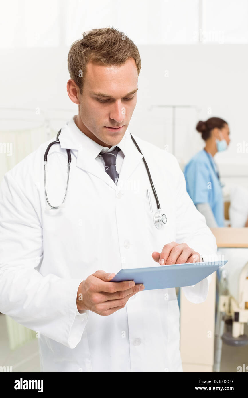 Doctor using digital tablet with colleagues and patient behind Stock ...