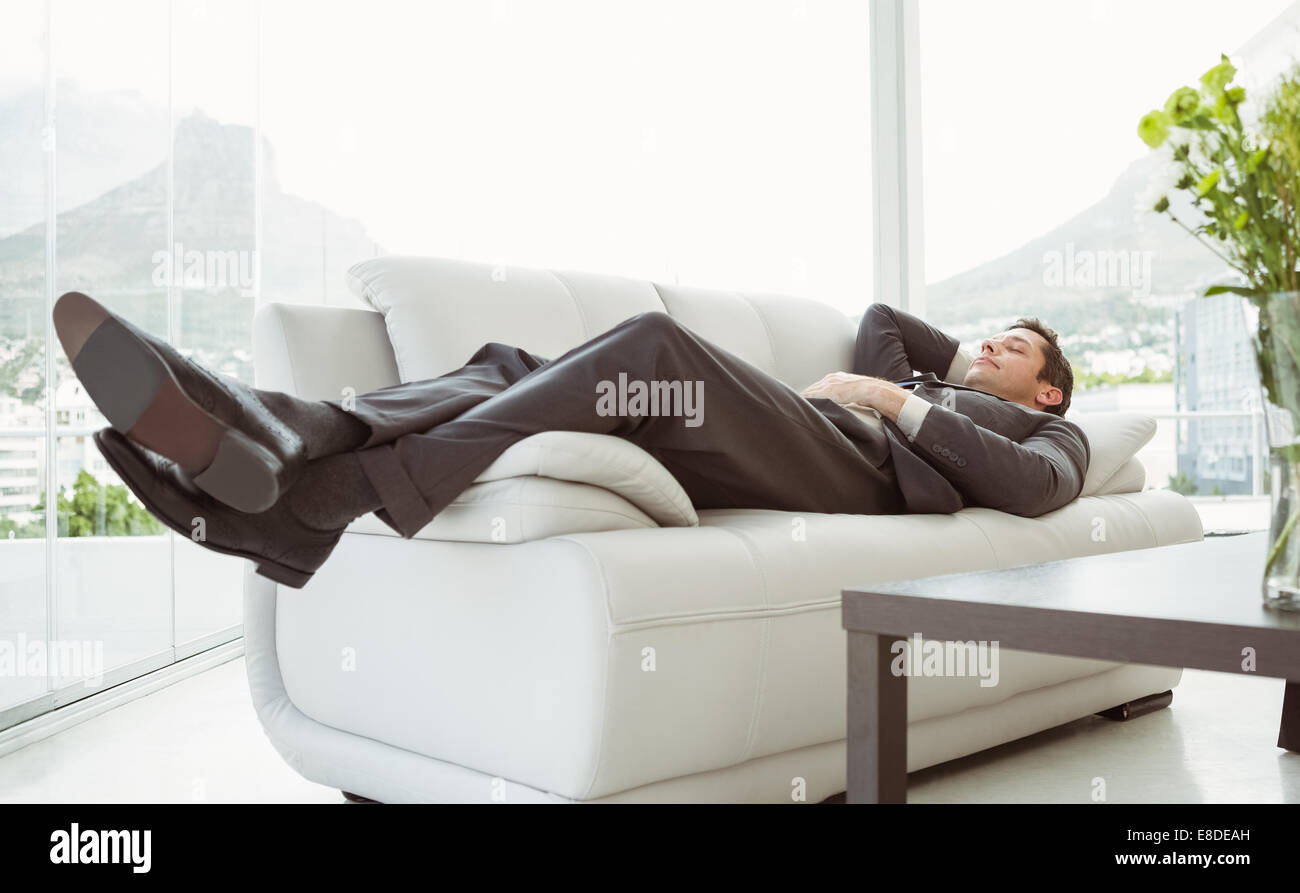 Young businessman lying on couch Stock Photo Alamy