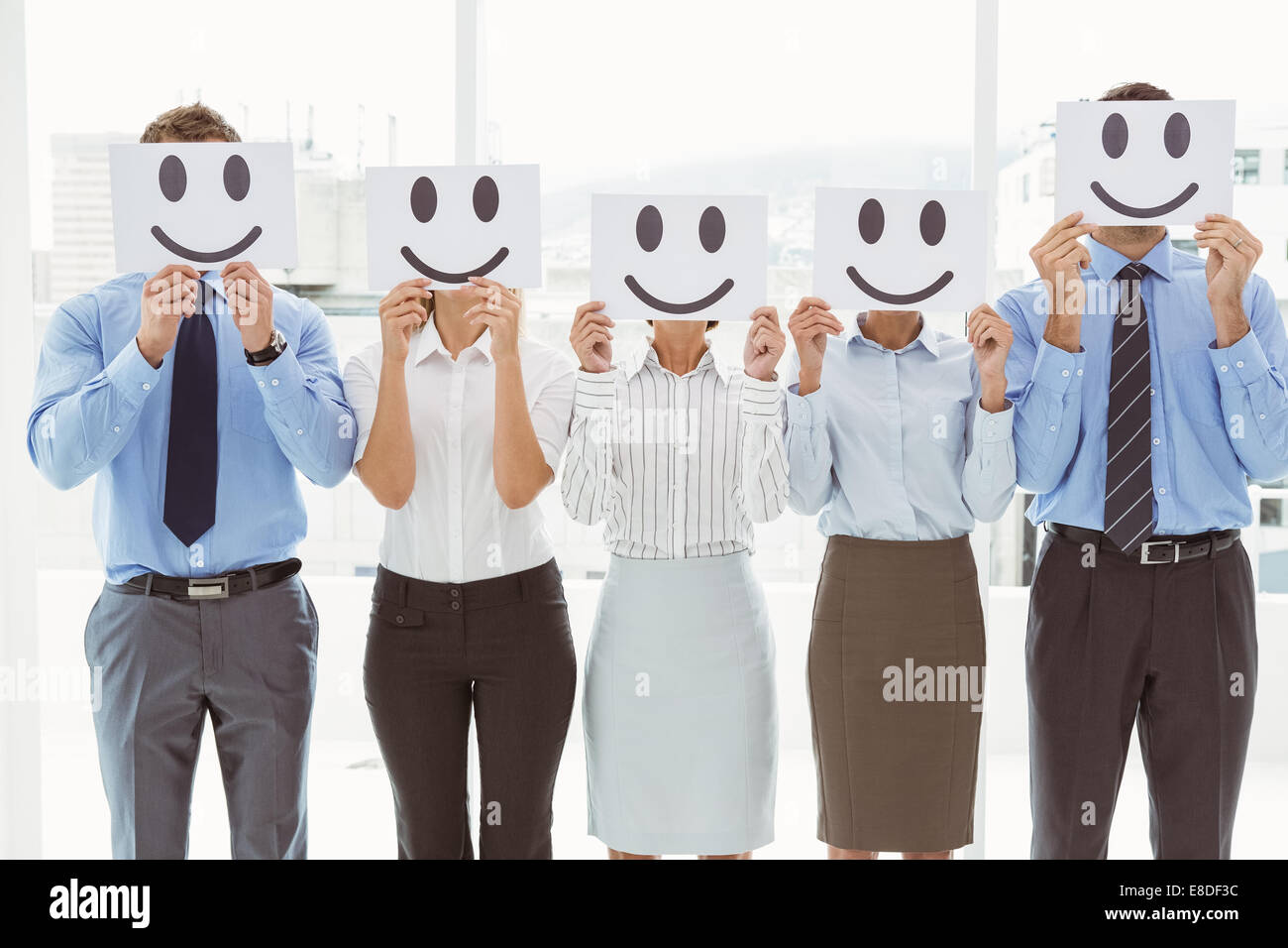 Business people holding happy smileys on faces Stock Photo