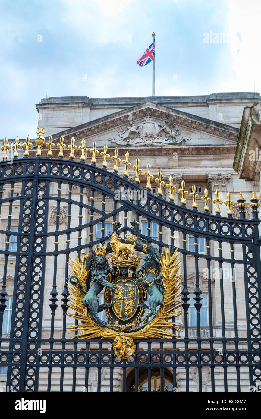 Detail of Buckingham Palace gates with Queen's crest and British flag atop the palace's facade in London, UK Stock Photo