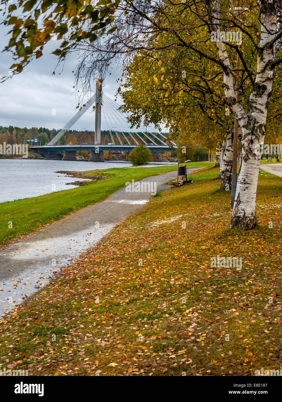 Park alley in autumn colors with bridge over the river in the background, Rovaniemi, Finland Stock Photo