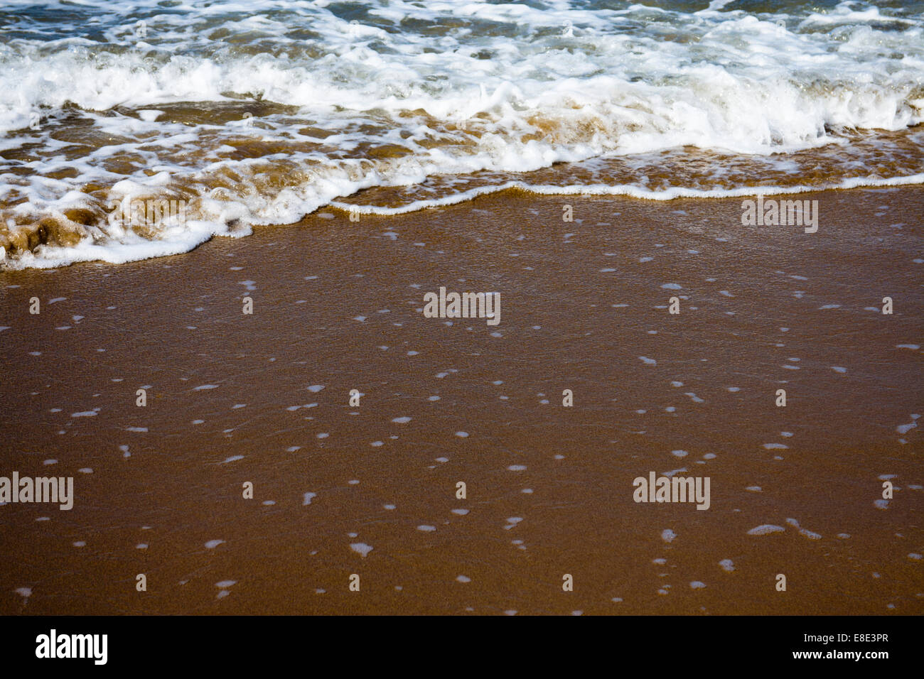 Shallow focus image of waves lapping onto a beach Stock Photo