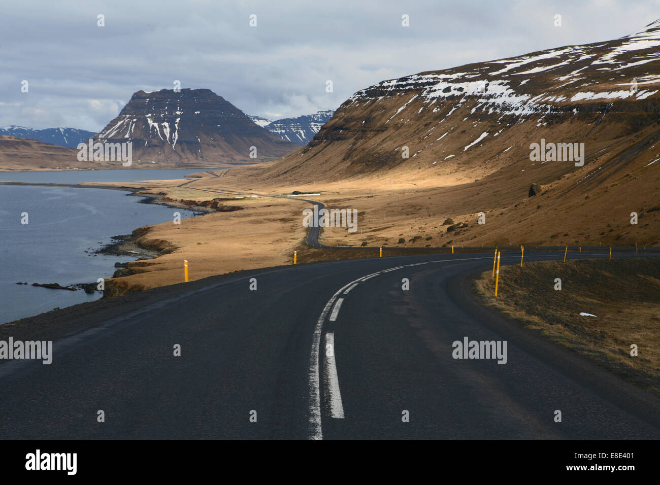 Icelandic road going off into the distance with the sea on the left hand side and mountains on the right Stock Photo