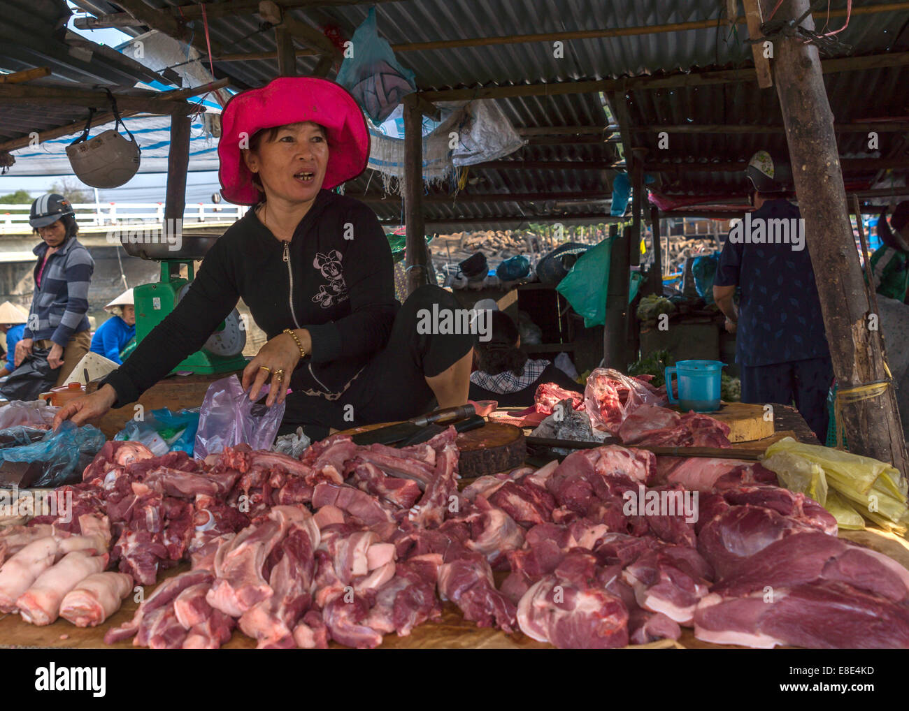 A female butcher sells her pieces of fresh cut meat in a simple booth at the market. Stock Photo