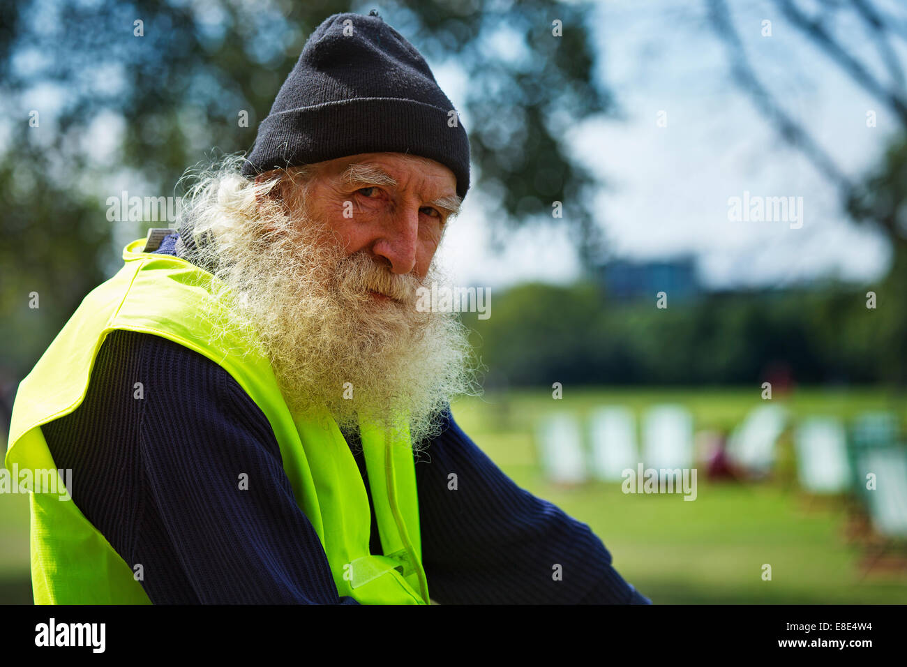 A man with a long gray beard sitting on a bike with high visibility vest on Stock Photo