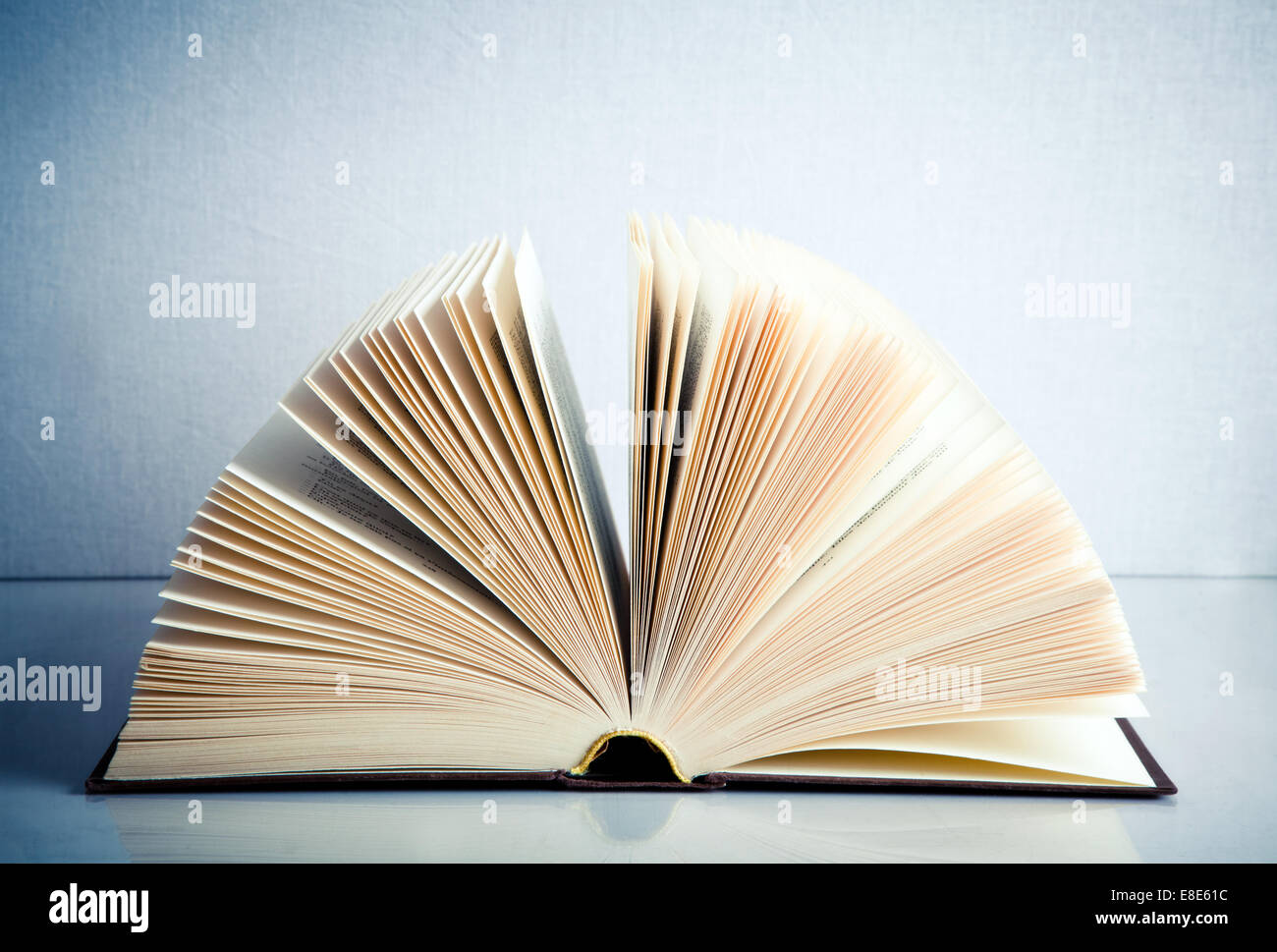 Fanned book on a white reflective surface Stock Photo
