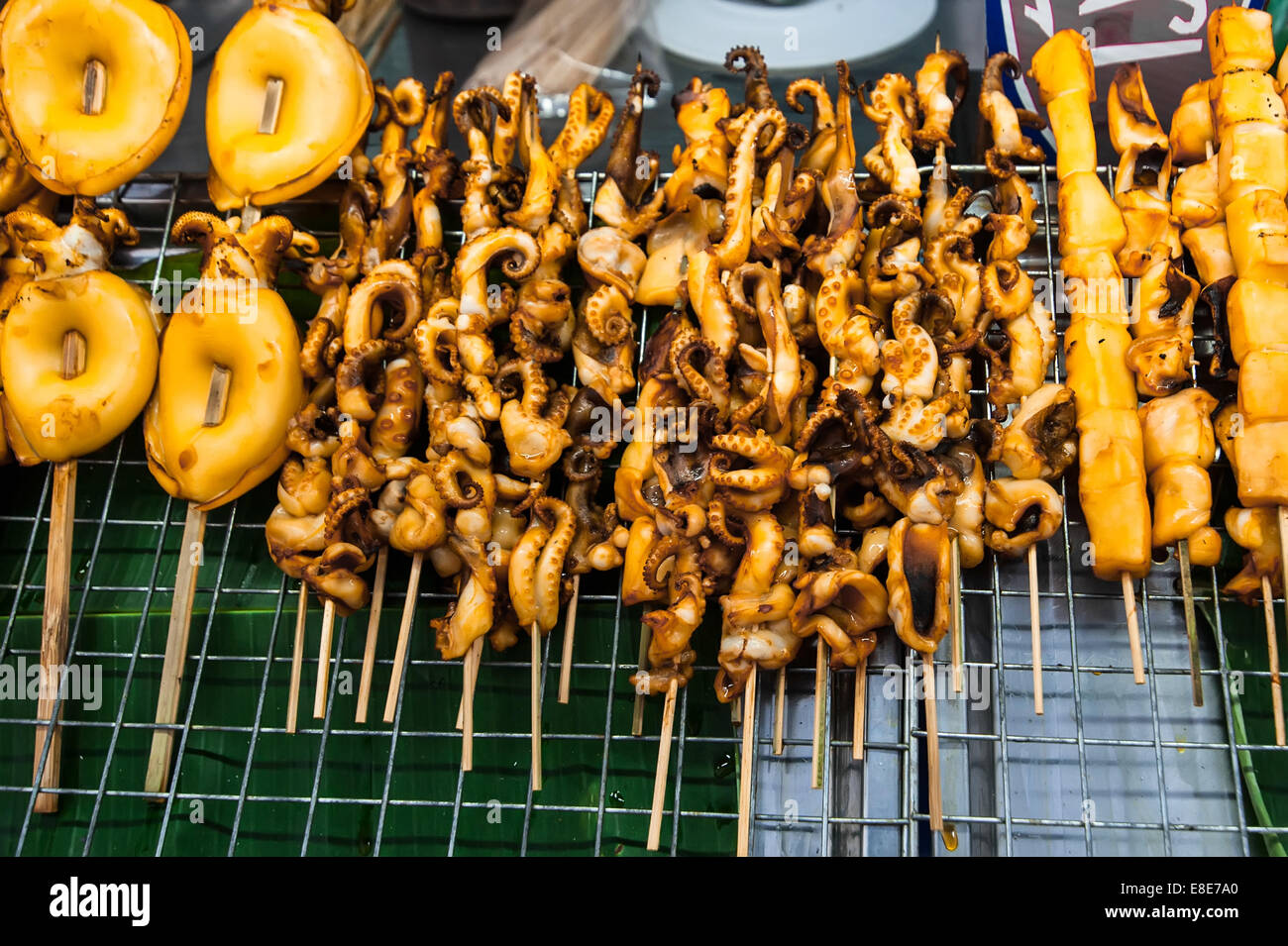 Traditional asian food at market. Grilled seafood on sticks. Calamari, octopus and cuttlefish. Loas Stock Photo