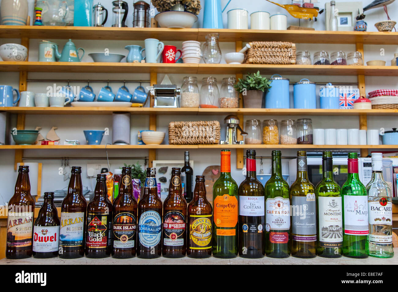 A line of beer & Wine bottles in a cottage kitchen. Stock Photo