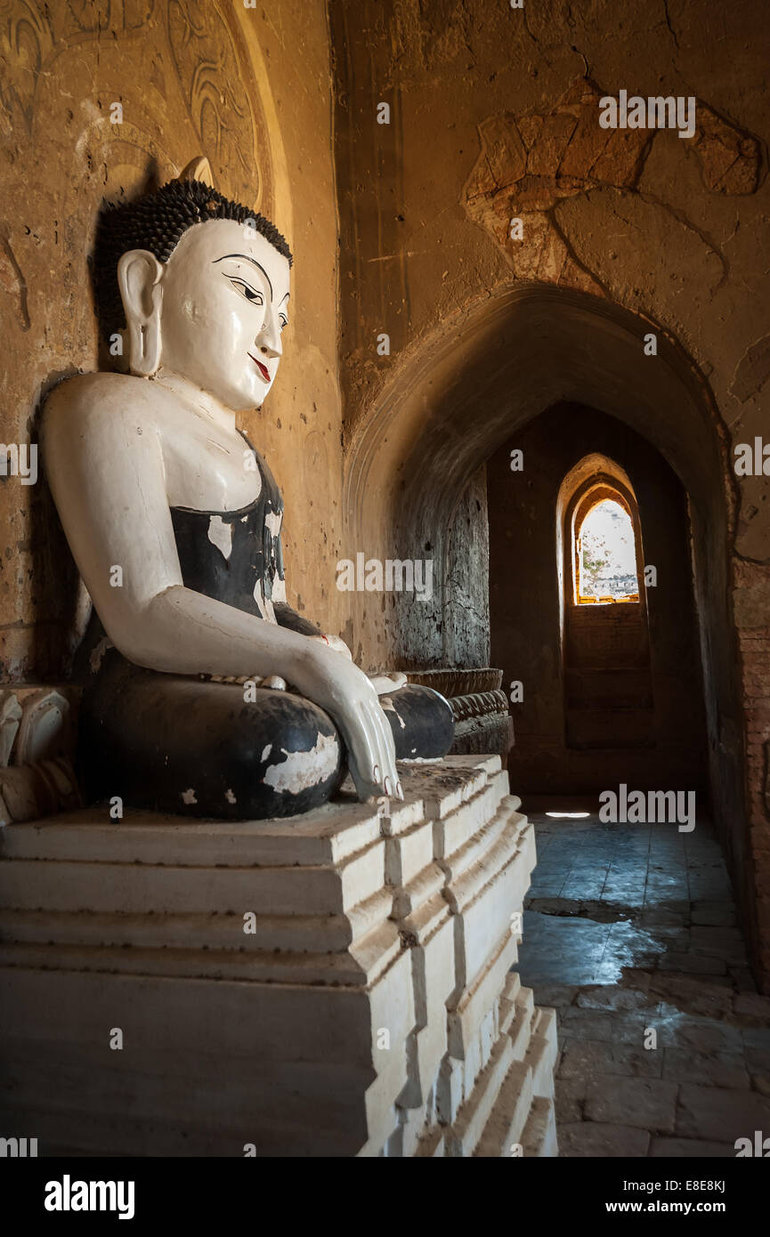 Ancient architecture of old Buddhist Temples at Bagan Kingdom, Myanmar (Burma). Golden Buddha statue inside one of pagoda ruins Stock Photo