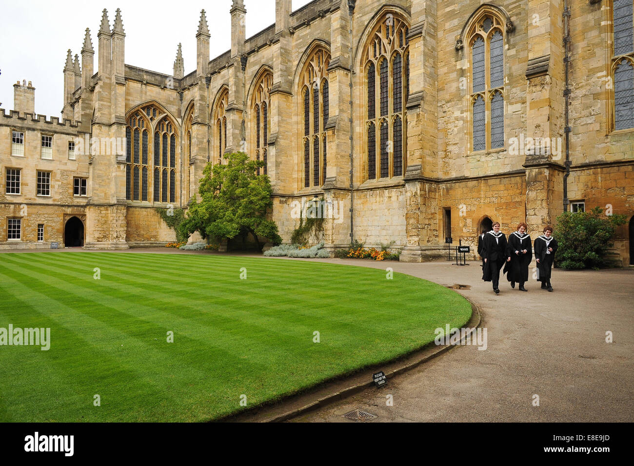3 graduates wearing sub fusc gowns walking in the quad inside New College Oxford, part of the University of Oxford, UK Stock Photo