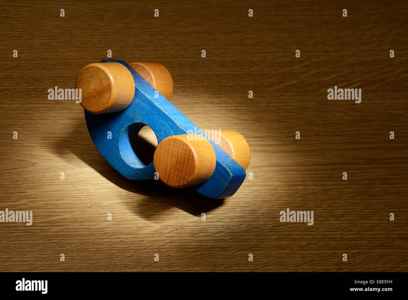 Spotlight on an upside down blue toy wooden car Stock Photo