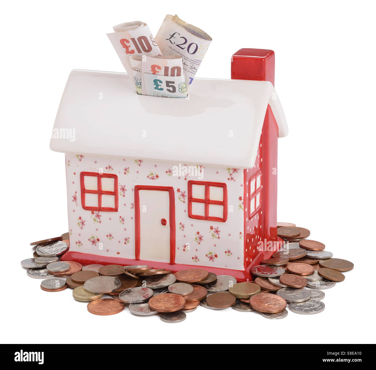 House shaped piggy bank with UK sterling coins and notes Stock Photo