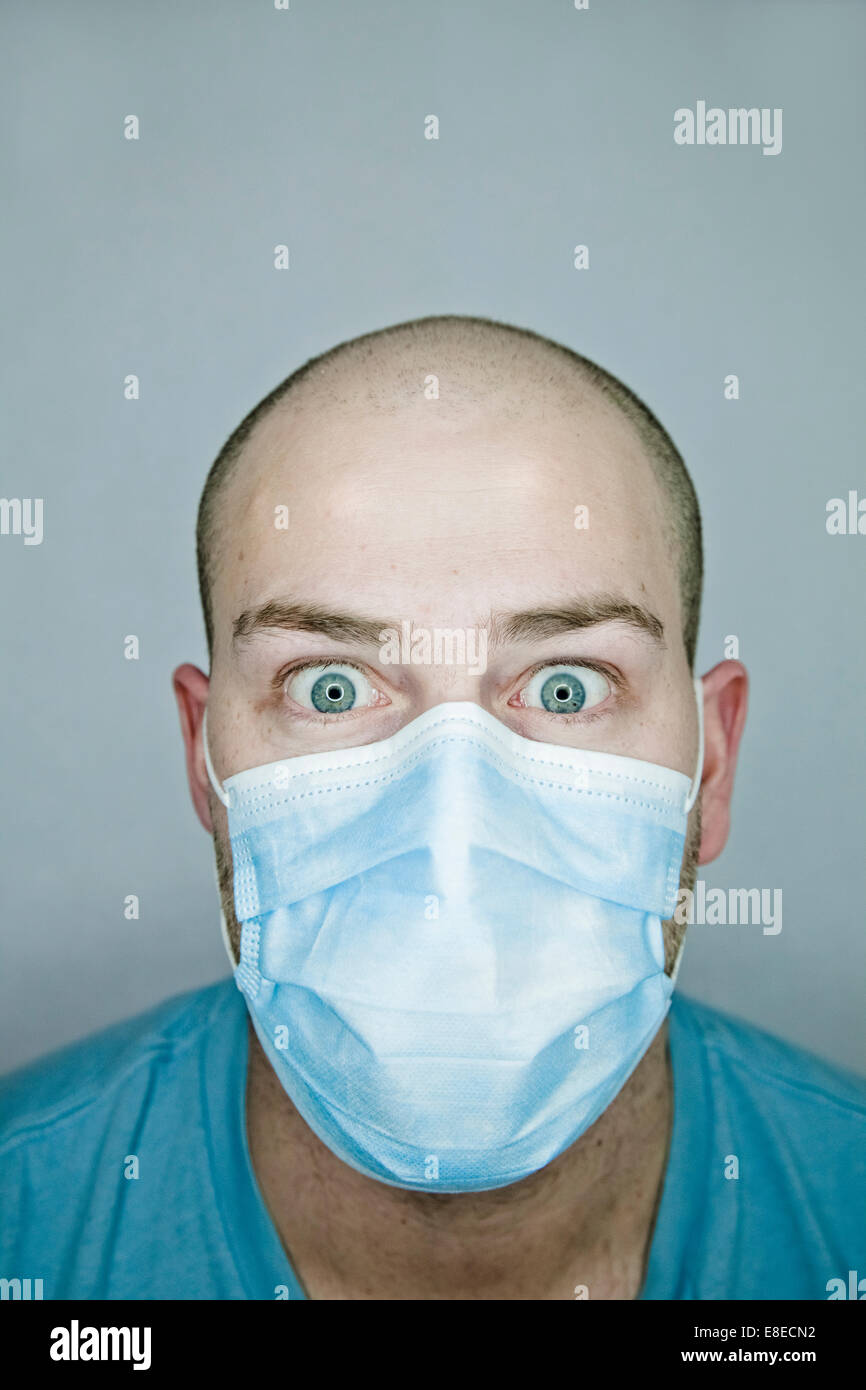 Young doctor with bald head wearing a mask and on a gray background (in studio) Stock Photo