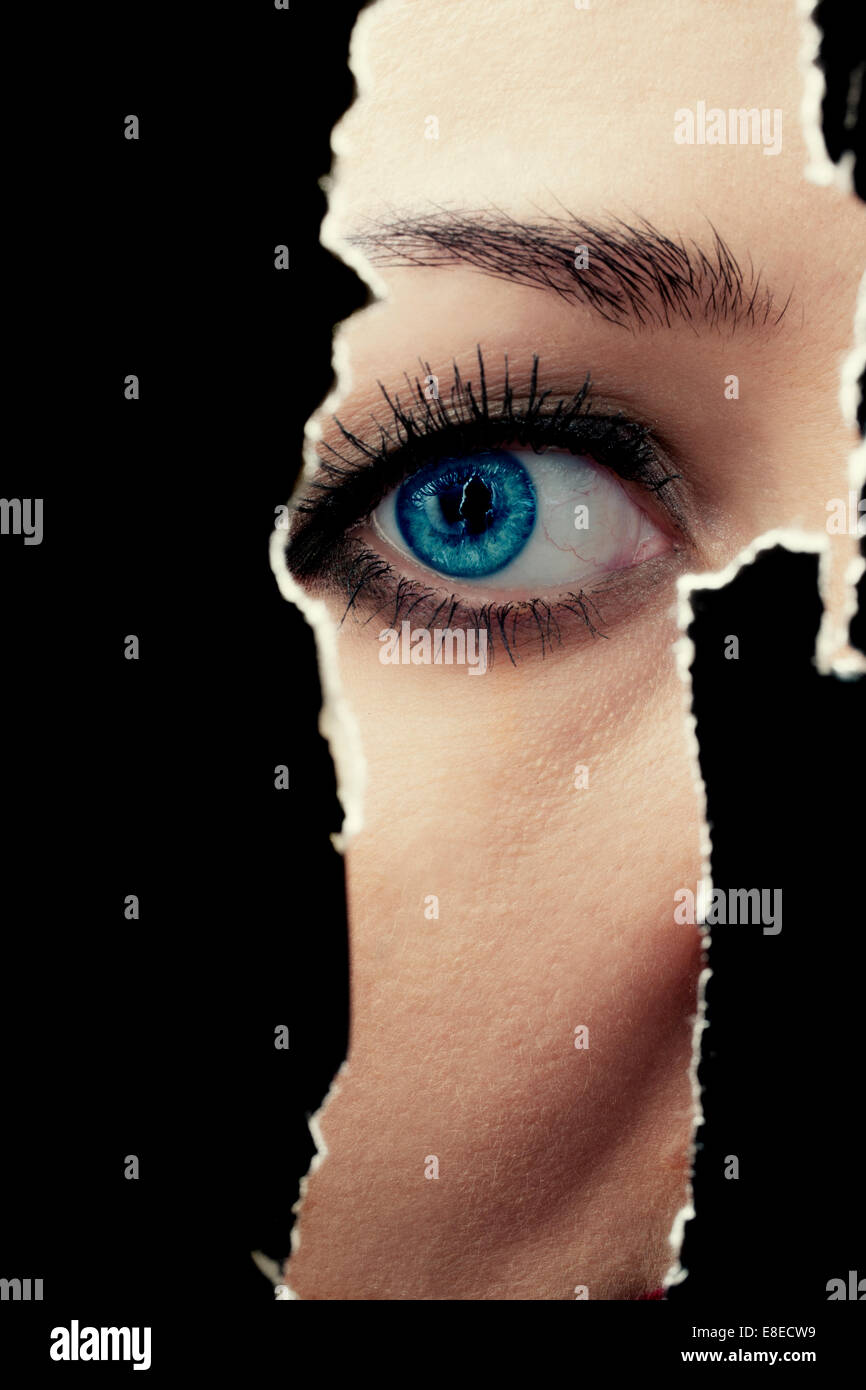 One eye of a young woman spying through a hole in the wall Stock Photo Alamy