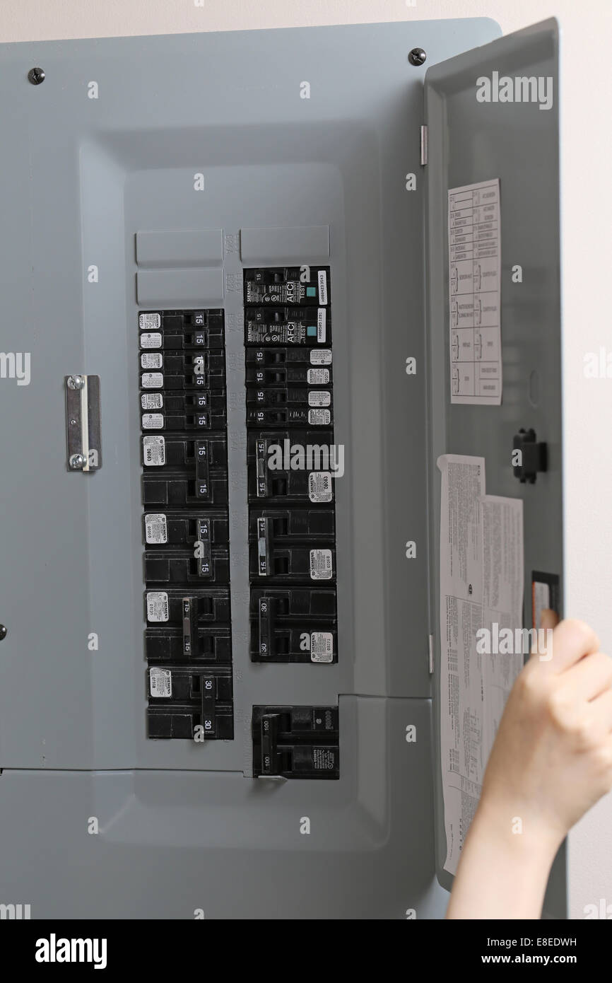 Woman checking automatic fuses at electrical control panel at home Stock Photo