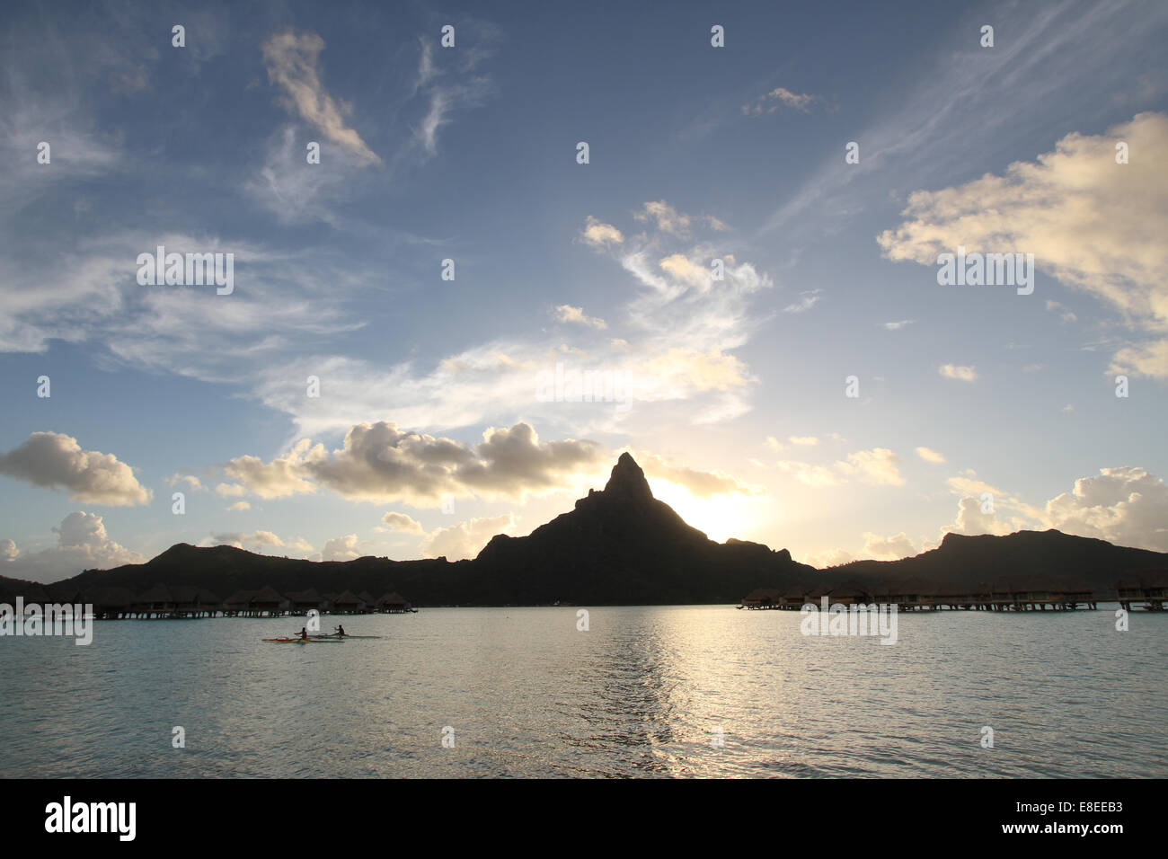 Outrigger at sunset in Bora Bora, French Polynesia with silhouette of mountain behind Stock Photo