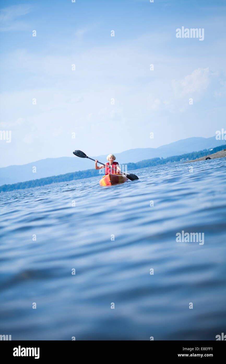 Young Woman Kayaking Alone on a Calm Sea and Wearing a Safety Vest