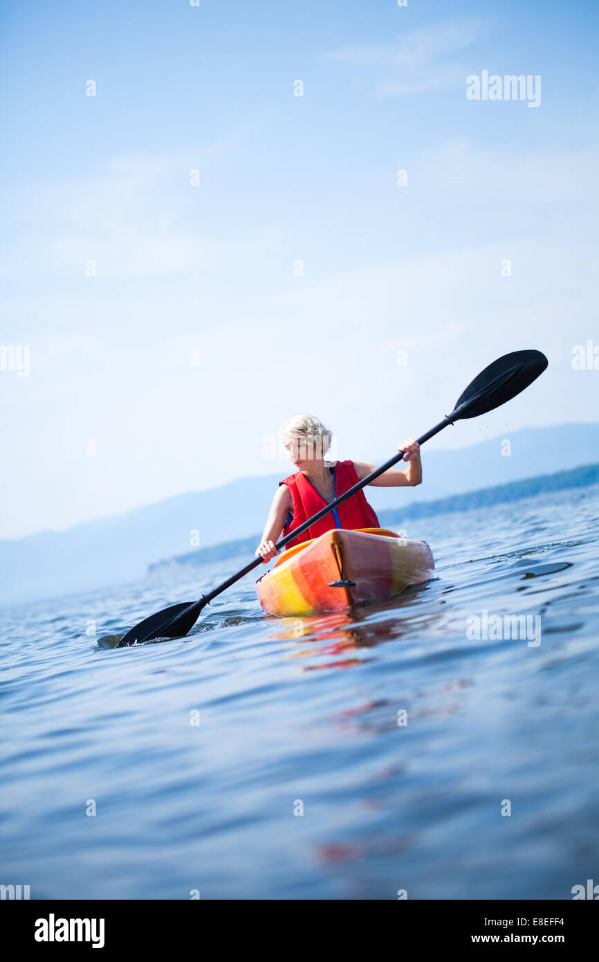 Young Woman Kayaking Alone on a Calm Sea and Wearing a Safety Vest