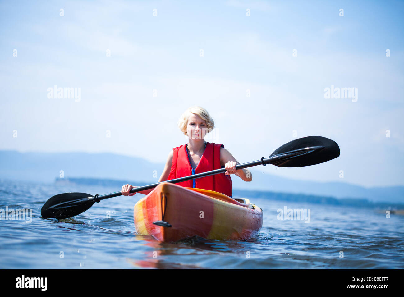 Young Woman Kayaking Alone on a Calm Sea and Wearing a Safety Vest