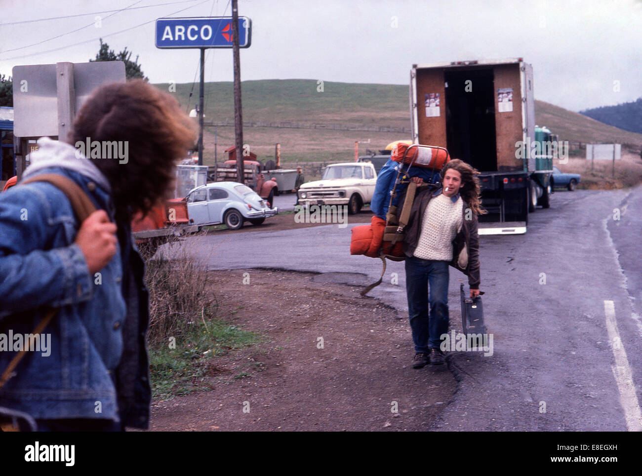 Young men teenager hippies hitchhiking (hitching a lift) past an ARCO gas station on Highway 101 California in USA 1977    KATHY DEWITT Stock Photo