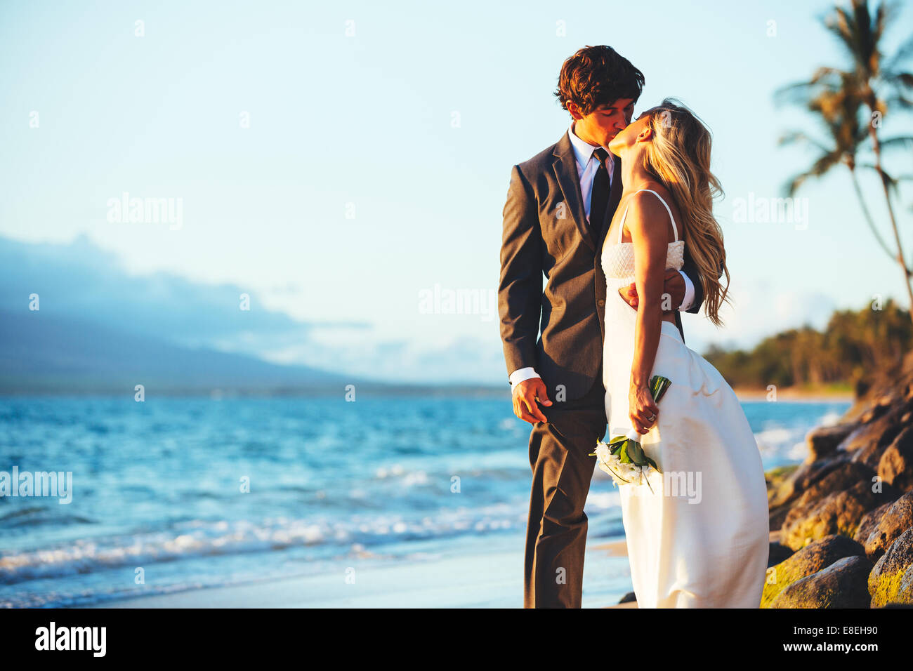 Romantic Wedding Couple Kissing on the Beach at Sunset Stock Photo