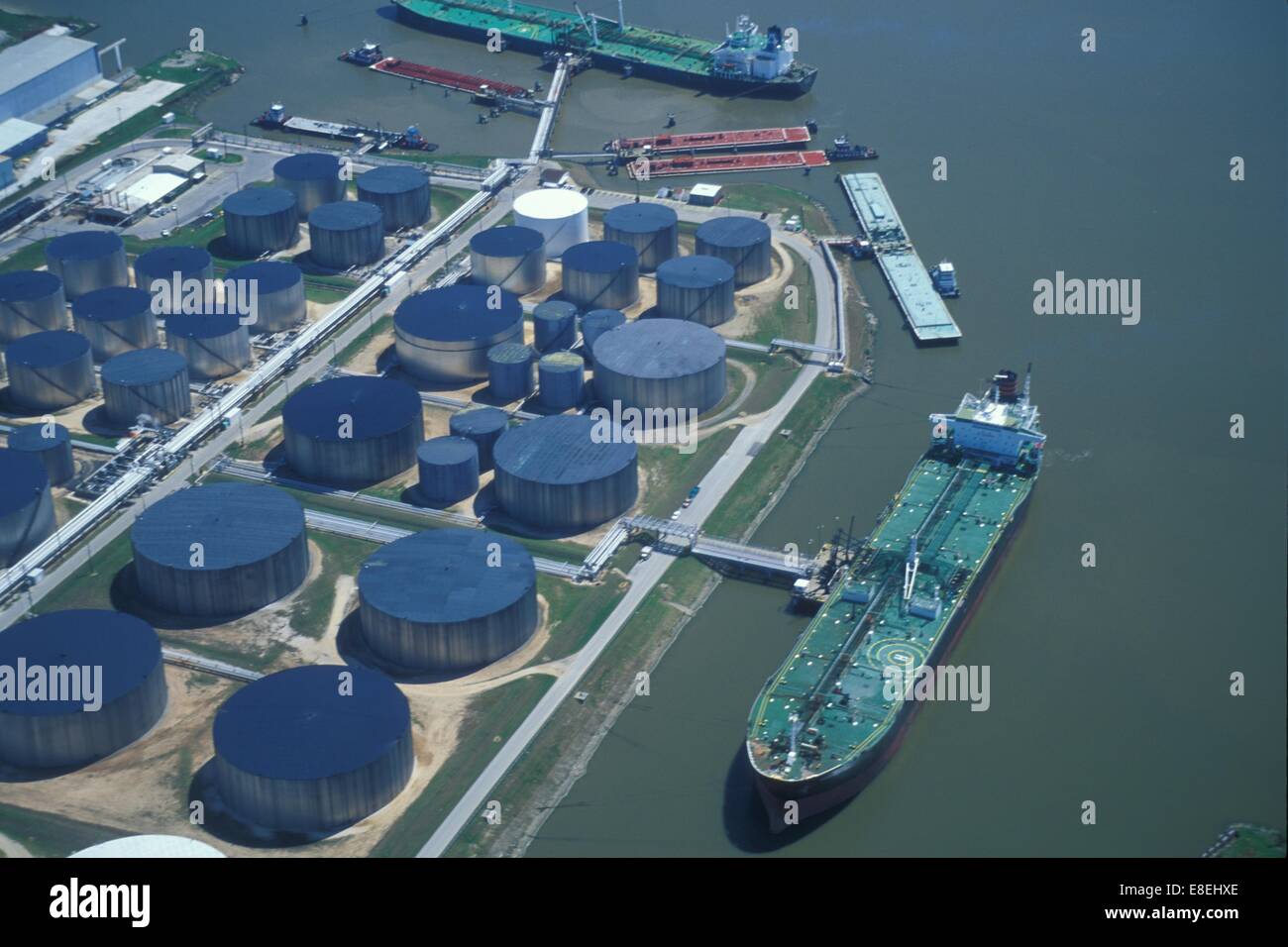 Two Oil Tankers Offloading at Oil Storage Facility with Blue Tanks Stock Photo