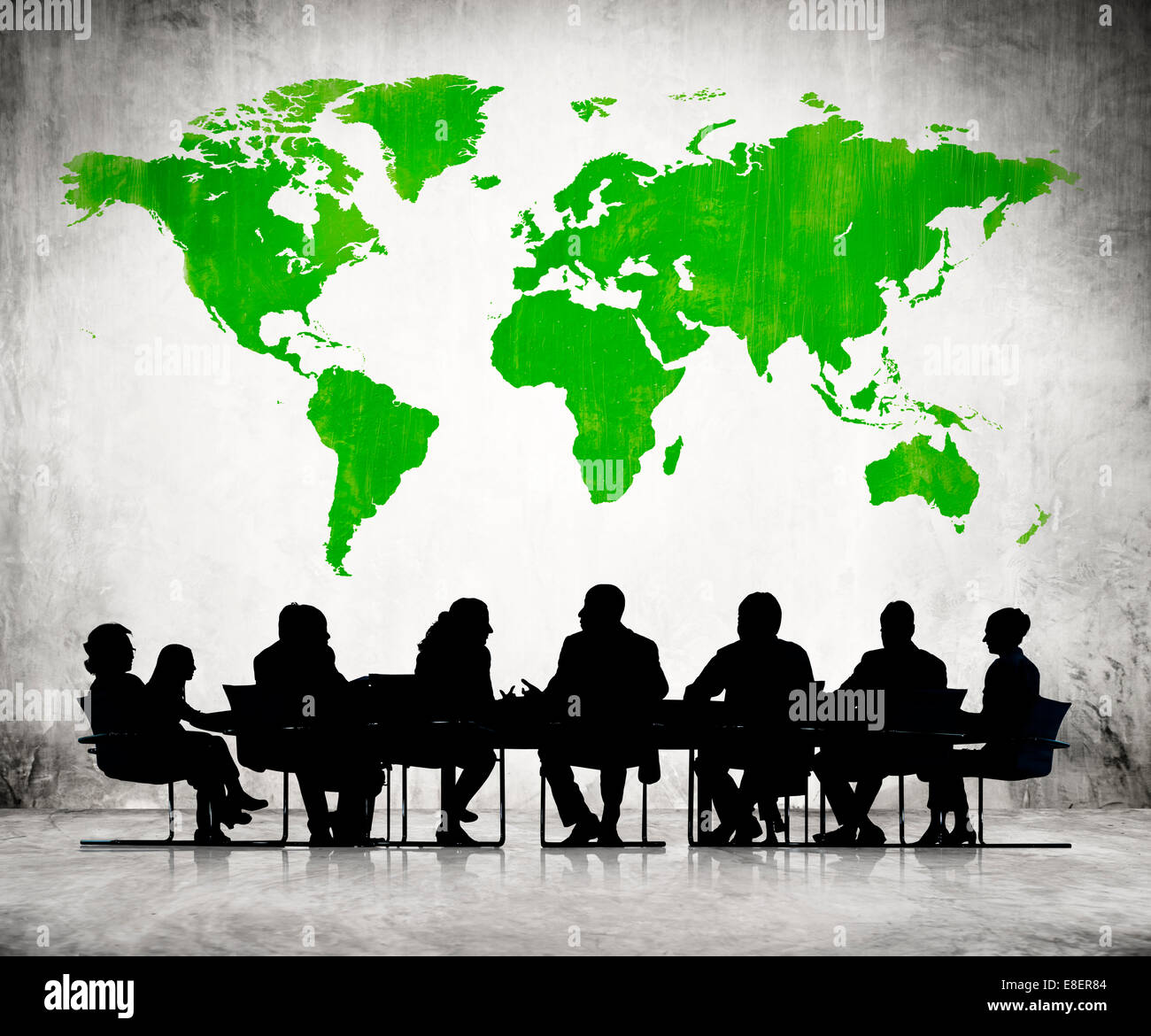 Business People Discussing Around The Conference Table And A Green Cartography Of The World Above Stock Photo