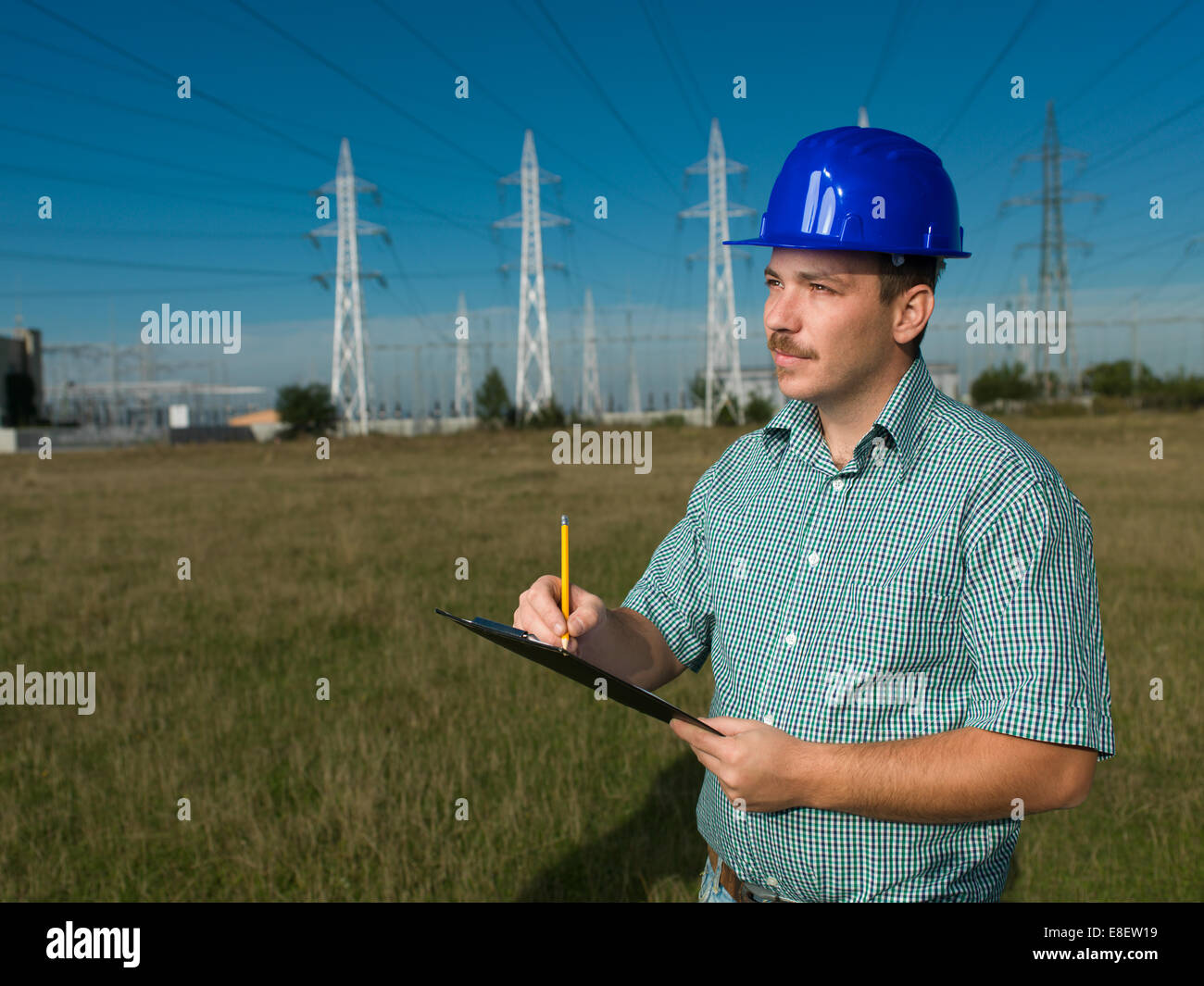 portrait of male technician writing on clipboard at electricity station Stock Photo