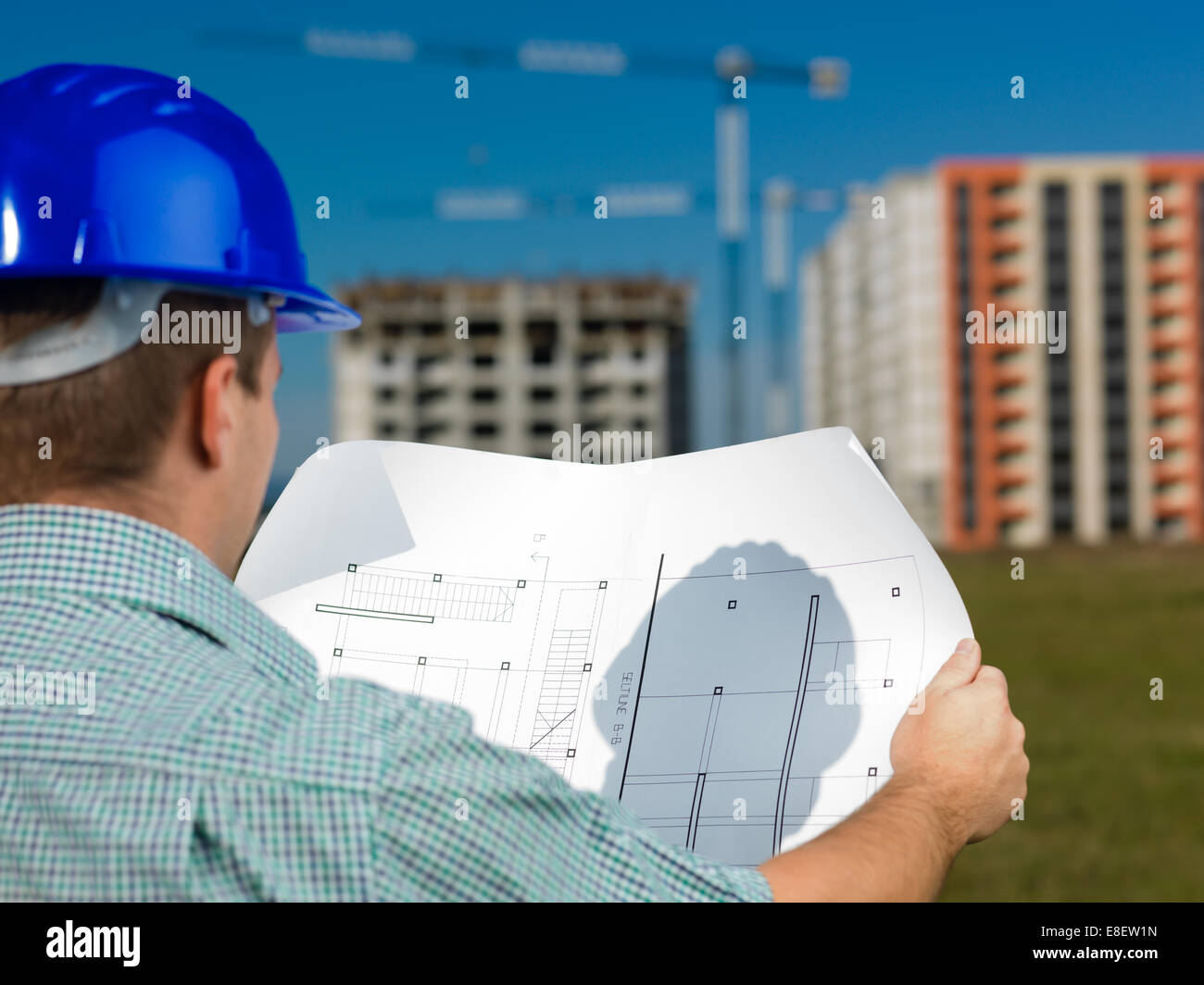 back view, closeup of male caucasian engineer at work looking at technical drawing plan Stock Photo