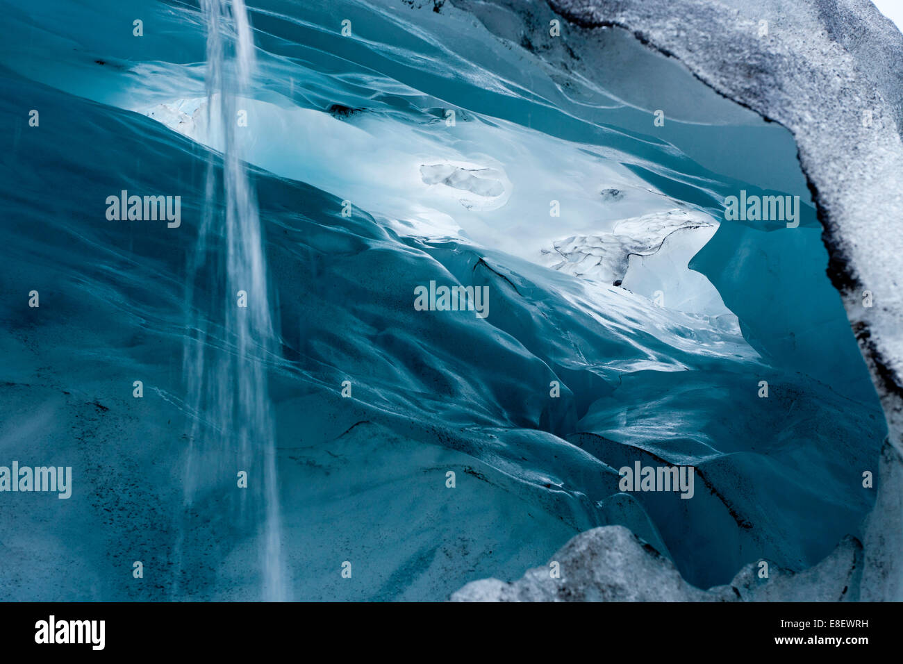 View into a blue-green ice cave with condensation water draining off, Skaftafell Glacier, Iceland Stock Photo