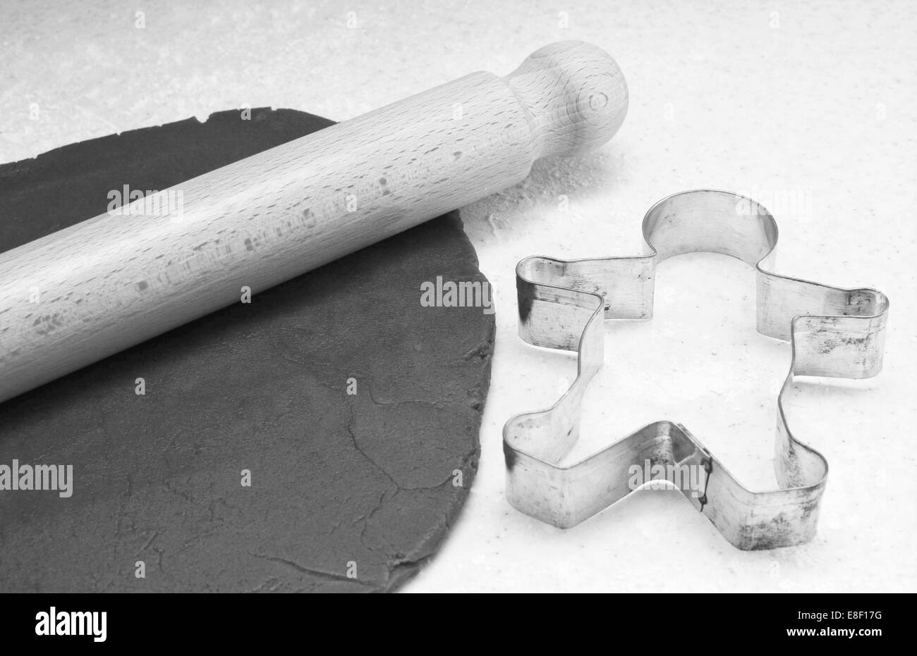 Gingerbread dough, wooden rolling pin and gingerbread man cookie cutter - monochrome processing Stock Photo