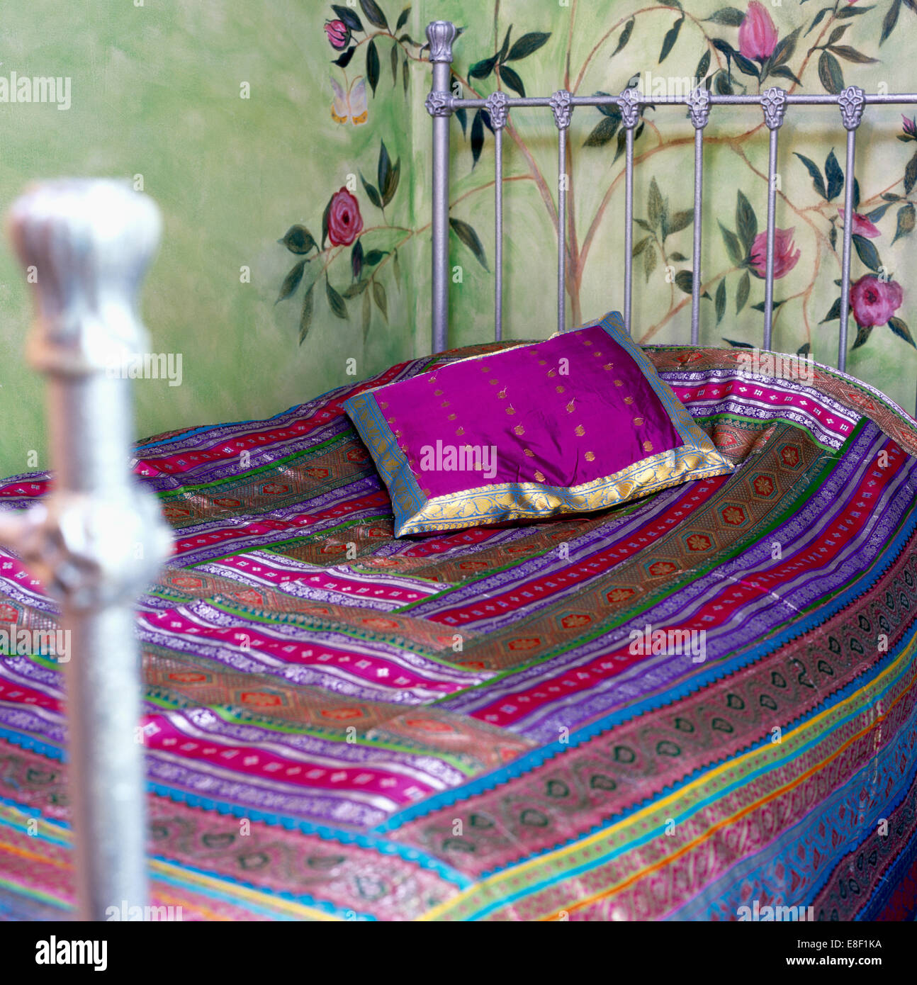 Purple Indian silk cushion on silver wroughtiron bed with patchwork Indian sarifabric quilt in