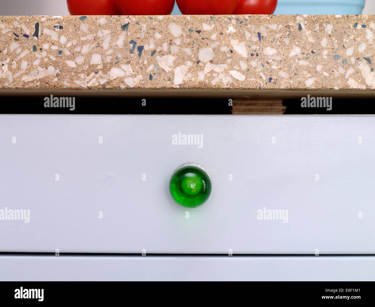 Close-up of kitchen drawer with green glass knob below terrazzo worktop Stock Photo