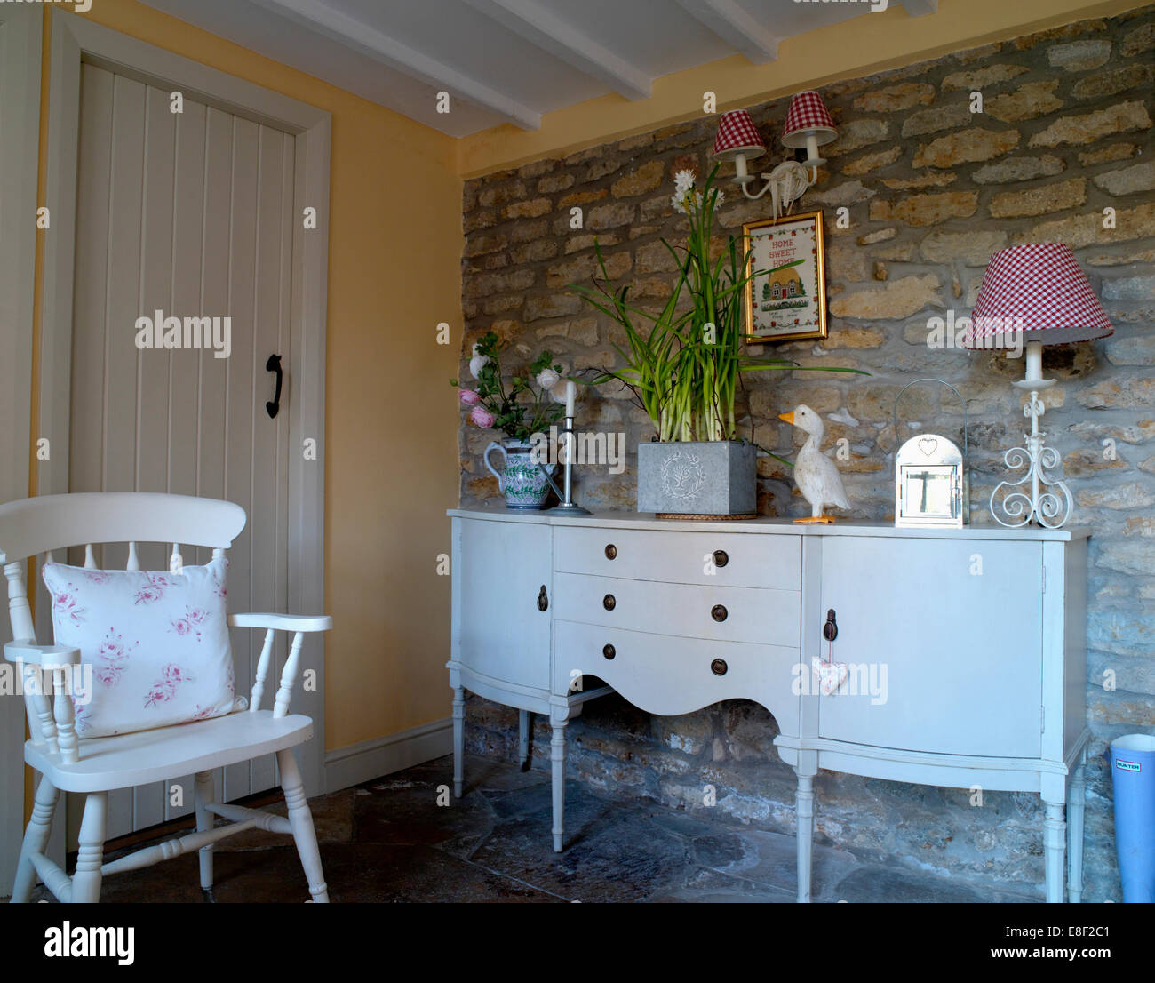 Painted white chair and sideboard in country hall with exposed stone wall Stock Photo