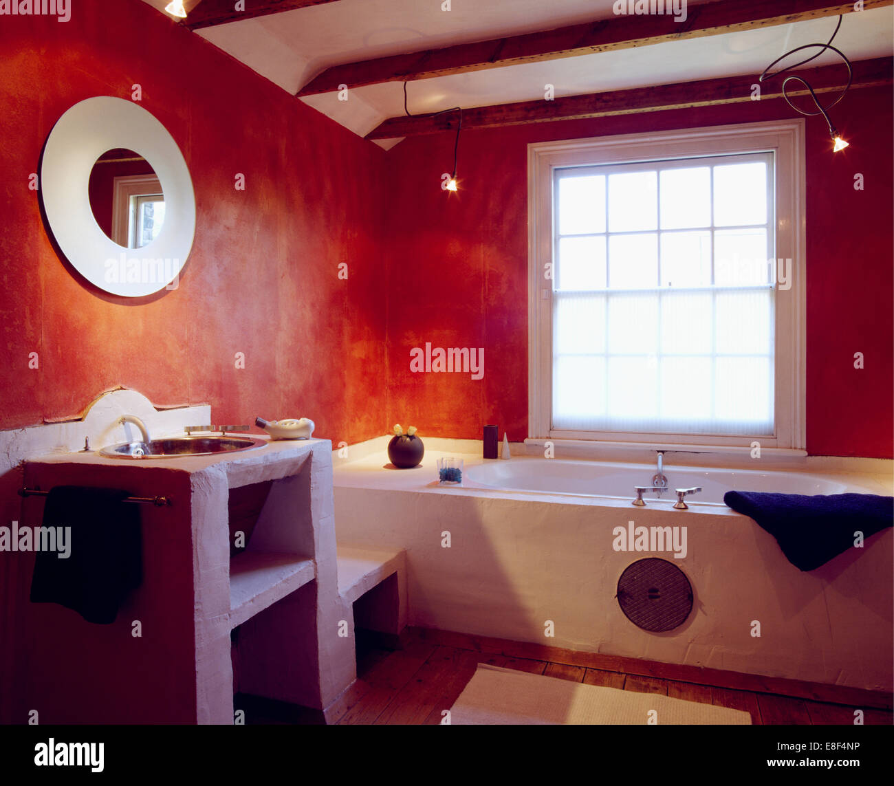 Circular mirror above basin in simple concrete vanity unit in economy