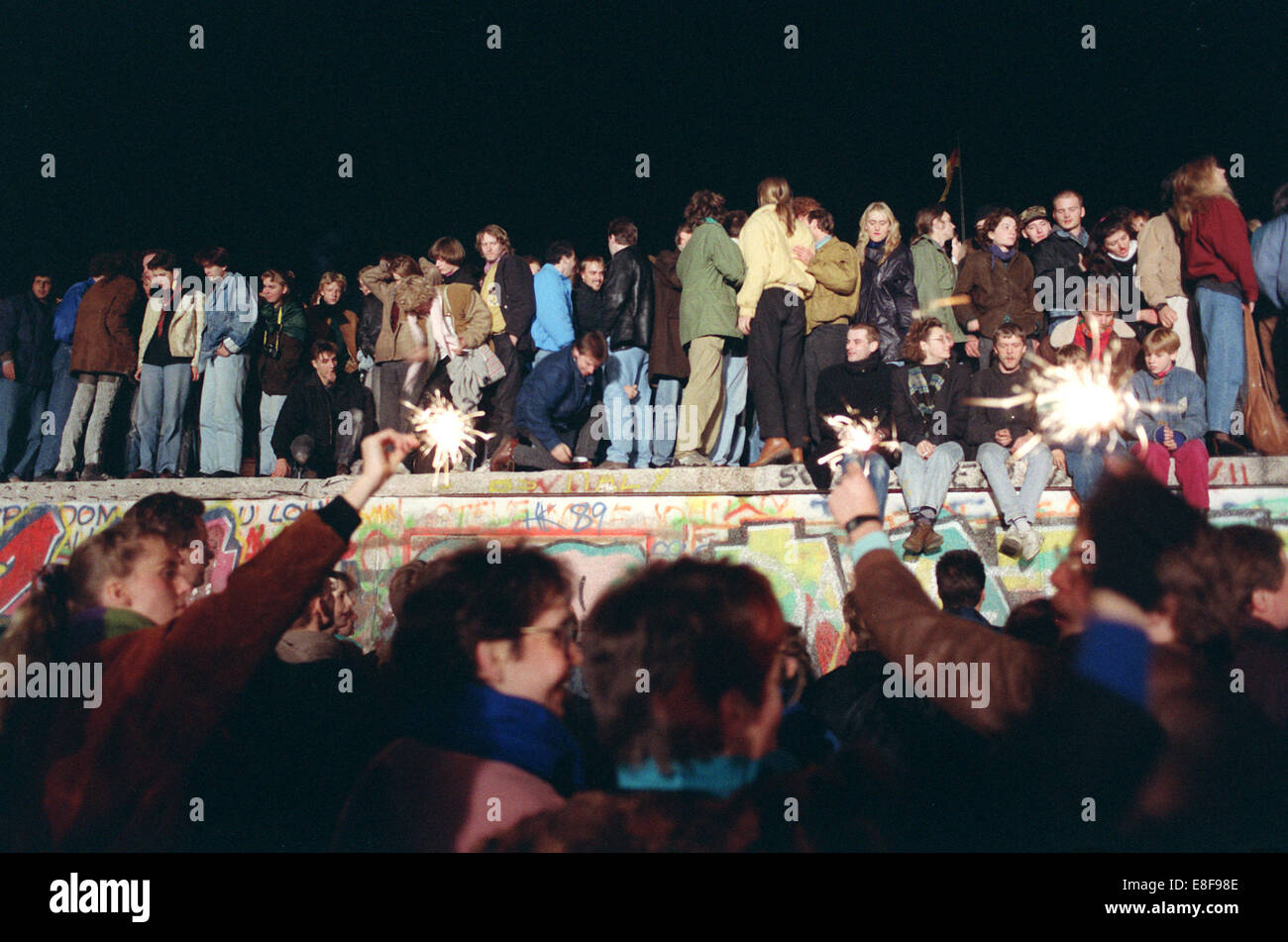 People sit on the Berlin Wall one day after the opening in Berlin, Germany, 10 November 1989. Photo: Peter Zimmermann Stock Photo
