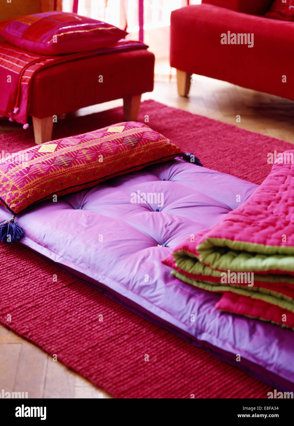 Close-up of folded pink+green quilt on purple silk futon mattress with pink  patterned cushion Stock Photo - Alamy