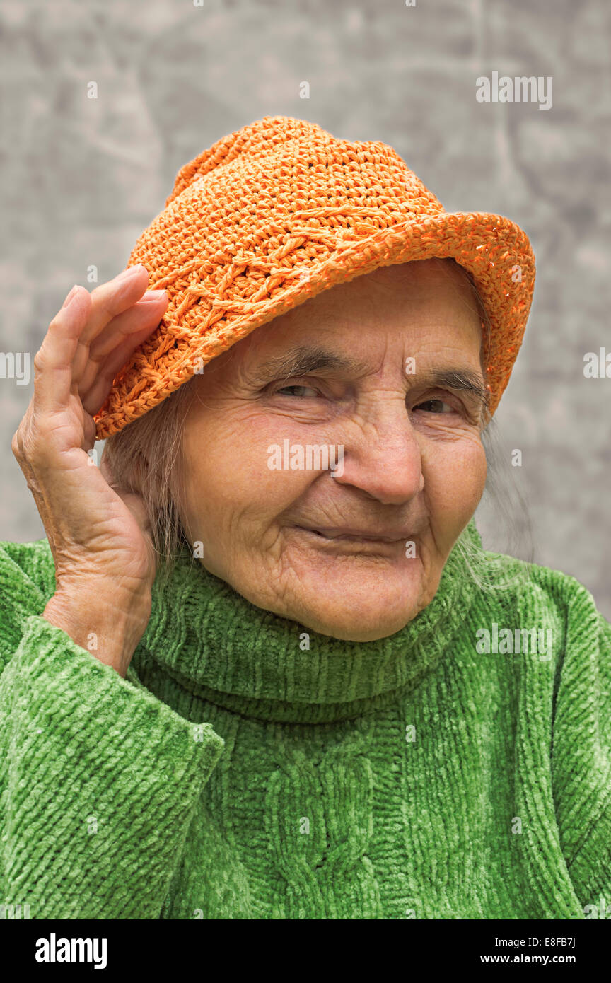 Elderly woman holding hand close to an ear. Hearing problems. Stock Photo
