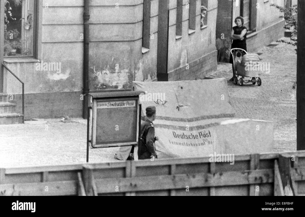 Border guards watching the opening of an incomplete escape tunnel to West Berlin. They disguised as post office clerks but were unmasked because of their boots. An escape tunnel was discovered across from the sector border at corner Eberswaler Street / Oderberger Street. The Federal Republic of Germany and the German Democratic Republic were split into west and east by an iron curtain from 13th August 1961, the day of the building of Berlin Wall, to the fall of the wall on 9th November 1989. Stock Photo