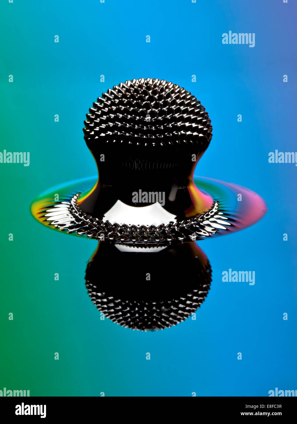 Macro of Ferrofluid structure induced by a neodymium magnet reflecting rainbow colored light Stock Photo