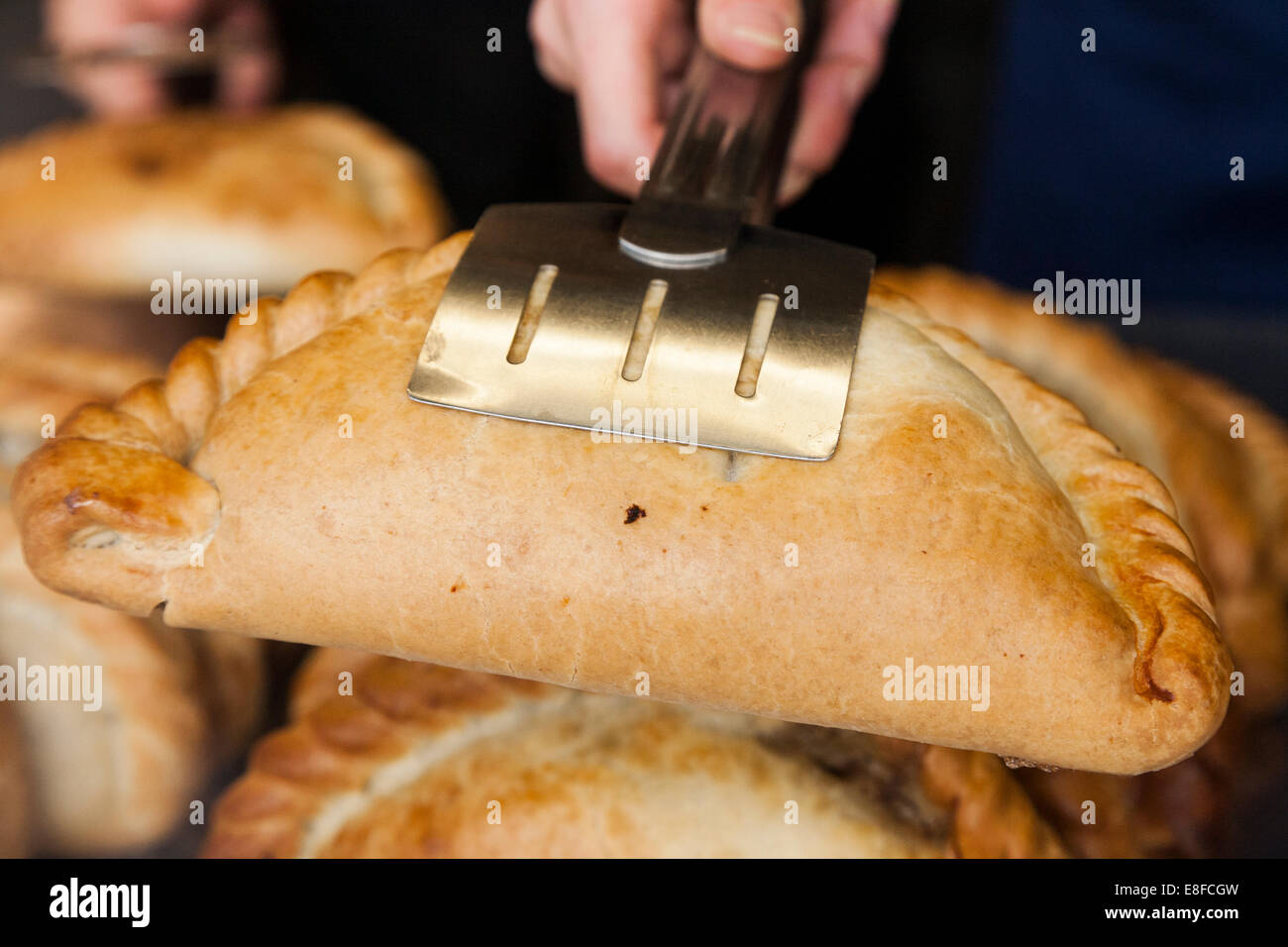 Picture of a Cornish pasty held by serving tongs in the display of a pasty shop. Mevagissey, Cornwall. UK. Stock Photo