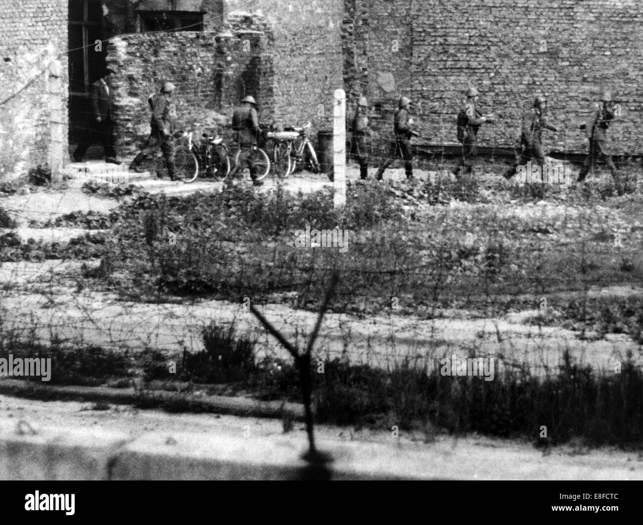 In 1962 border guards from East Berlin leave a bordering house to West Berlin, in which they have discovered an escape tunnel. From the 13 August 1961, the day of the building of the Berlin Wall, to the fall of the Berlin Wall on the 9 November 1989 the Federal Republic of Germany and the GDR were separated by the iron curtain between West and East. Stock Photo