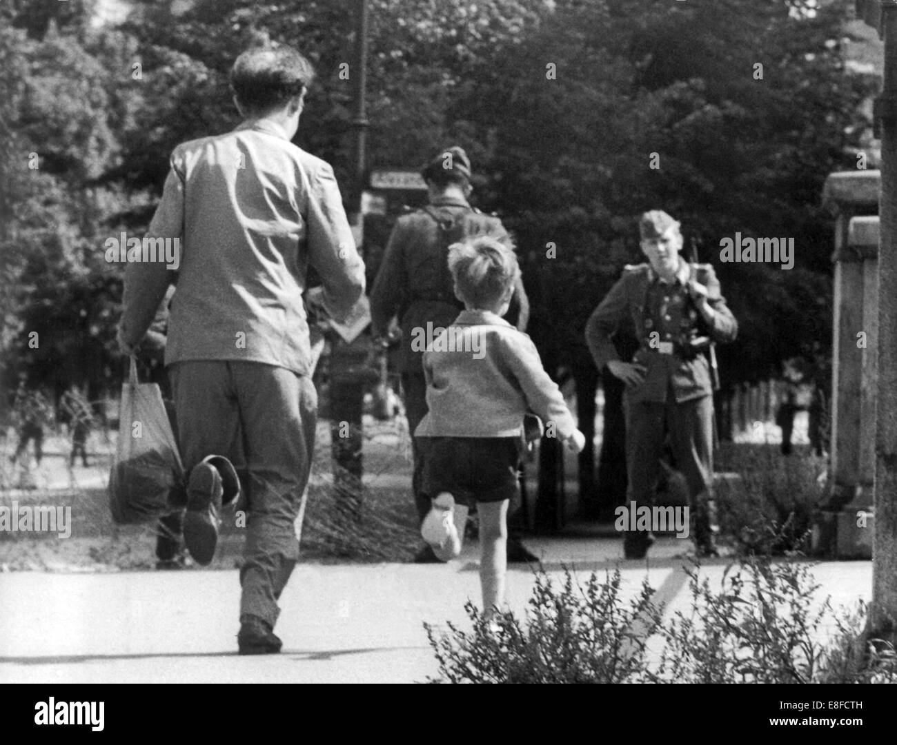 A father and his little son run in the direction of East Berlin after the surprising sealing off of West Berlin by the rulers of the GDR on the 13th of August in 1961. The People's Police of the GDR had allowed to bring back the child, which was on a visit to West Berlin. Stock Photo