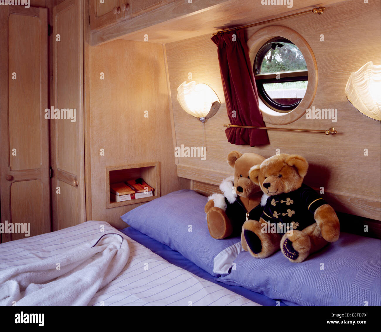 Walllights on either side of porthole above bed with teddy bears and