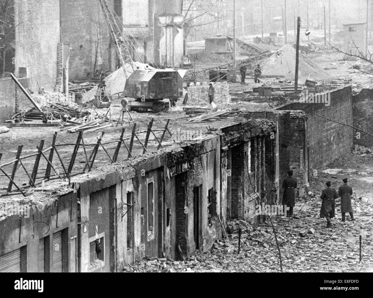 Building workers from East Berlin are tearing down the last houses near Bernauer Street in Berlin, 16 January 1967. The tenants of the house were resettled in the course of the compulsory evacuation. From 13 August 1961, the day of the building of the Berlin Wall, until the fall of the Berlin Wall on 9 November 1989, the Federal Republic of Germany and the GDR were separated by the iron curtain between West and East. Stock Photo