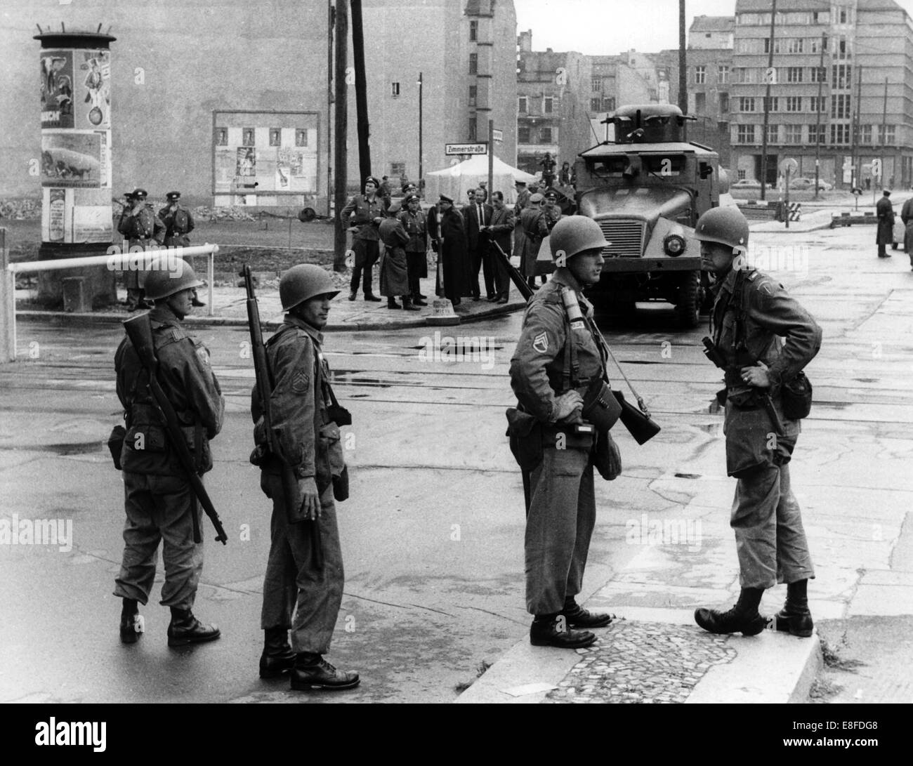 Soldiers of the US Army standing on the western side of Berlin and People's Police officers of the GDR, with water guns, standing on the eastern side of Berlin on 24th August 1961 at checkpoint Friedrichstraße in Berlin. From the 13th August 1961, the day of the construction of the Wall, until the fall of the Wall on the 9th November 1989, the Federal Republic of Germany and the GDR were seperated into West and East by an 'Iron Curtain'. Stock Photo